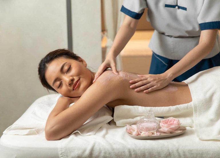 Spa Therapist Applies Rose Body Scrub To The Back Of A Woman