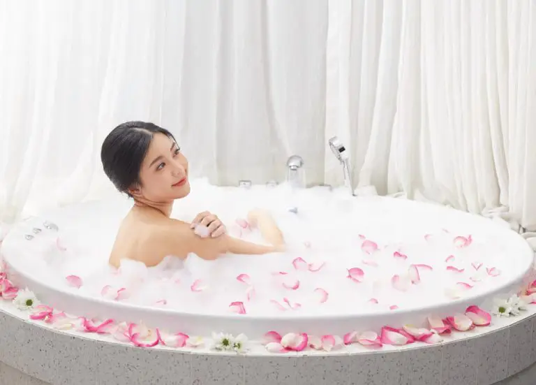 Woman Relaxing At Spa In Bubble Bath Among Rose Petals